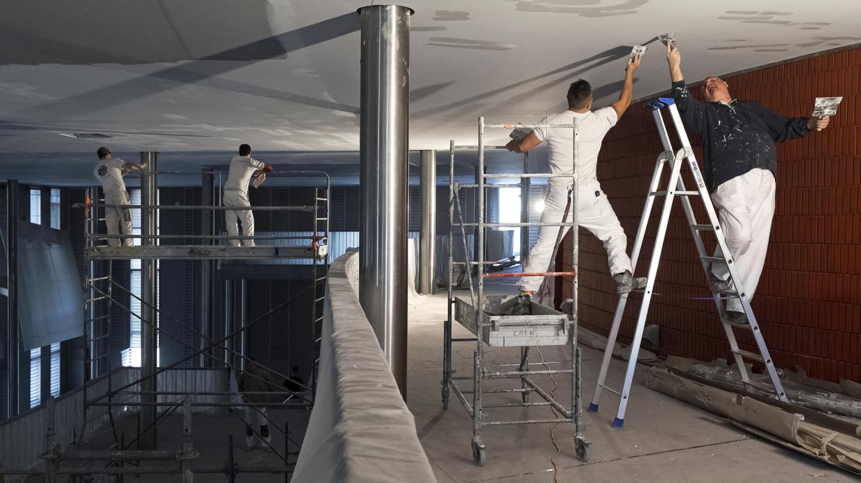 Deux hommes sur un escabeau peignent le plafond des foyers du théâtre.