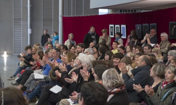 Public applaudissant dans les foyers du théâtre.